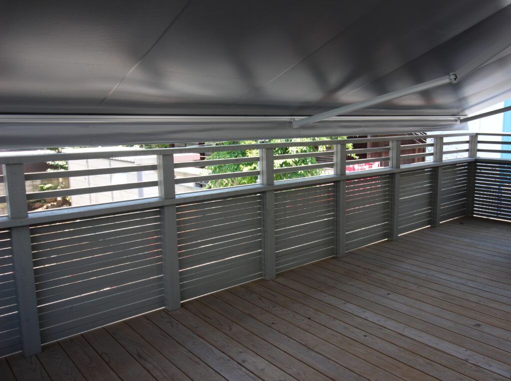 デザインフェンスが印象的なガレージデッキ　オーニングを広げたところ　デッキ内部から　文京区