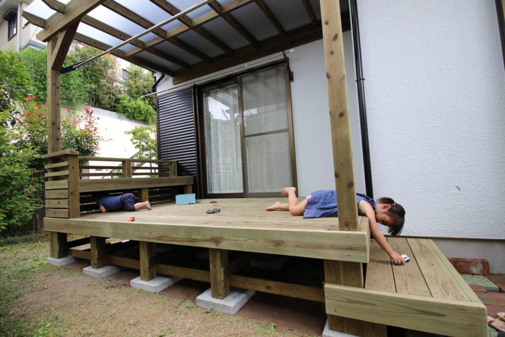 国産スギで長持ちするデッキで子供たちが腹ばいで遊んでいる　町田市