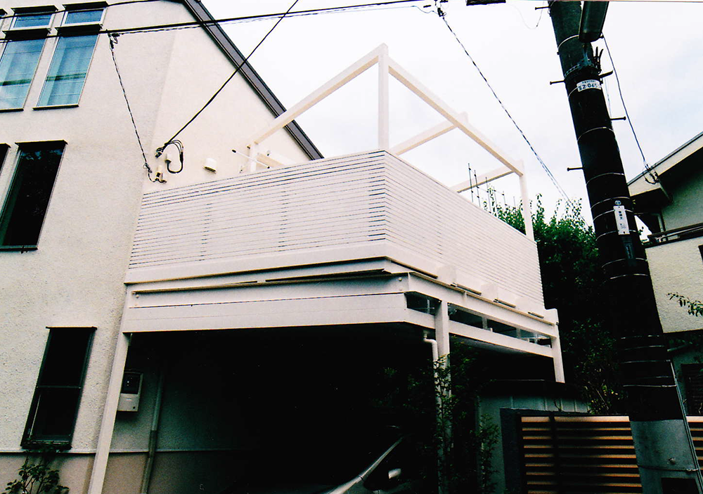 東京都世田谷区N様邸　鉄骨架台のウッドバルコニー。がっしりとしたパーゴラと街並みにとけこむ白いデッキがポイント